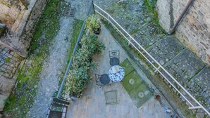 Vista aérea de un patio con suelo de piedra, una pequeña mesa y sillas, plantas en macetas y una bicicleta.