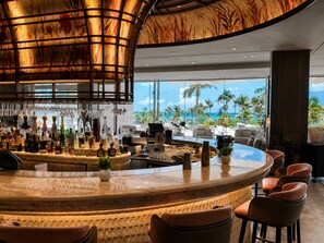 Eine Bar mit einer gebogenen Theke, Barhocker und Blick auf den Ozean.