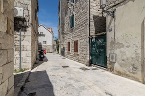 A narrow street with stone buildings, a motorbike parked on the side, and a clear sky. - Casa di Pietra Apartment (Split)