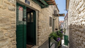 A narrow stone building with a green door, a small balcony with potted plants, and a visible window. - Casa di Pietra Apartment (Split)