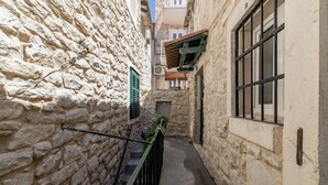A narrow stone alleyway with a metal railing and a small door at the end. - Casa di Pietra Apartment (Split)