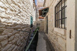 A narrow stone alleyway with a metal railing and a small door at the end. - Casa di Pietra Apartment (Split)