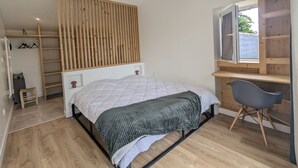 Een slaapkamer met een bed, een bureau, een stoel, een kledingkast en een raam.
