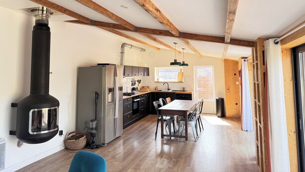 Een keuken met een grote kookplaat, een koelkast en een eettafel met stoelen.