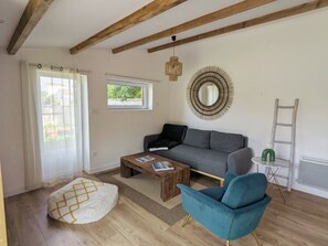 Ein Wohnzimmer mit einer Couch, einem Couchtisch, einem blauen Sessel, einer Holzzahlende und einem Wandspiegel.