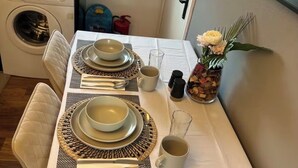 Una tavola da pranzo ordinata con piatti, ciotole, posate e un vaso di fiori.