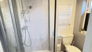 Un bagno moderno con cabina doccia in vetro, un water e un lavandino.