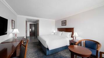 A hotel room with a bed, desk, chair, and a television.
