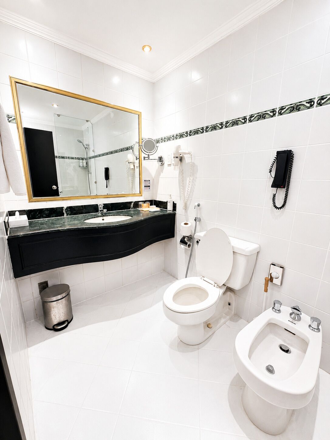 A modern bathroom with a toilet, bidet, and a large mirror.
