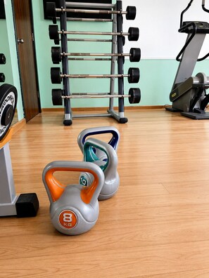 A gym with weightlifting equipment, including kettlebells and a barbell rack.