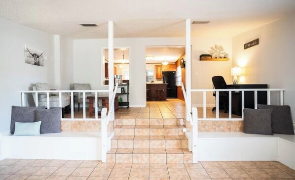 A living room with a staircase leading to a kitchen, a dining area, and a hallway.