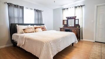 A bedroom with a bed, a dresser, a mirror, and curtains.