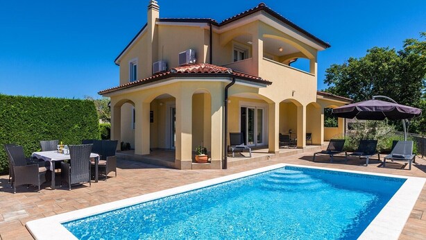 Uma casa de dois andares com piscina, área de estar ao ar livre e varanda coberta.