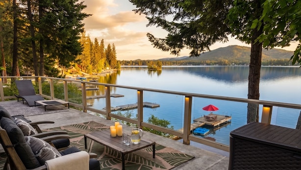 Una terraza con mobiliario exterior, una mesa con velas y vistas a un lago.