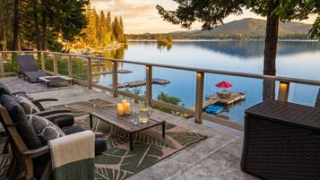 Une terrasse dotée de mobilier d’extérieur, d’une table décorée de bougies et offrant une vue sur un lac.