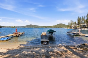 Un muelle sobre el lago con barcos, un embarcadero de madera y un bosque en el fondo.