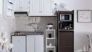 Eine kleine Küche mit weißen Schränken, einer eingebauten Mikrowelle und einem kleinen Kühlschrank.