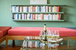 Ein Zimmer mit Glastisch, einer Champagnerflasche und vier Gläsern auf einem Tablett.