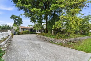 A residential driveway leading to a house with a basketball hoop, surrounded by trees and a stone wall. - Coastal Escape Minutes from Cherry Grove! (North Myrtle Beach)