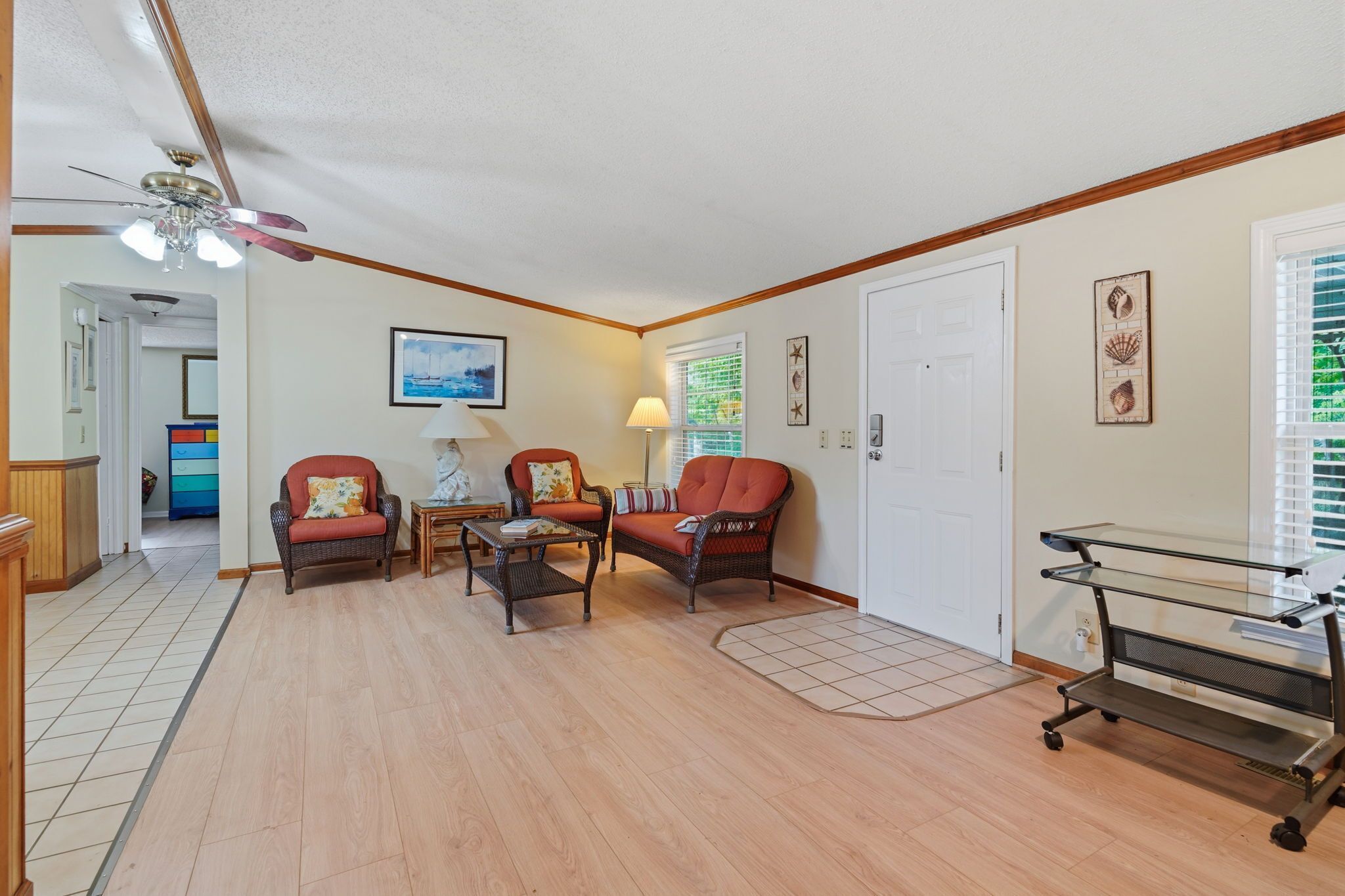A living room with a ceiling fan, a dining area with a table and chairs, and a door with a window.