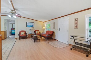 A living room with a ceiling fan, a dining area with a table and chairs, and a door with a window.