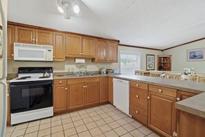 A kitchen with wooden cabinets, a stove, microwave, and a dishwasher.