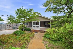 A single-story house with a covered porch, a front yard with a concrete pathway, and a wooden fence in the background. - Coastal Escape Minutes from Cherry Grove! (North Myrtle Beach)
