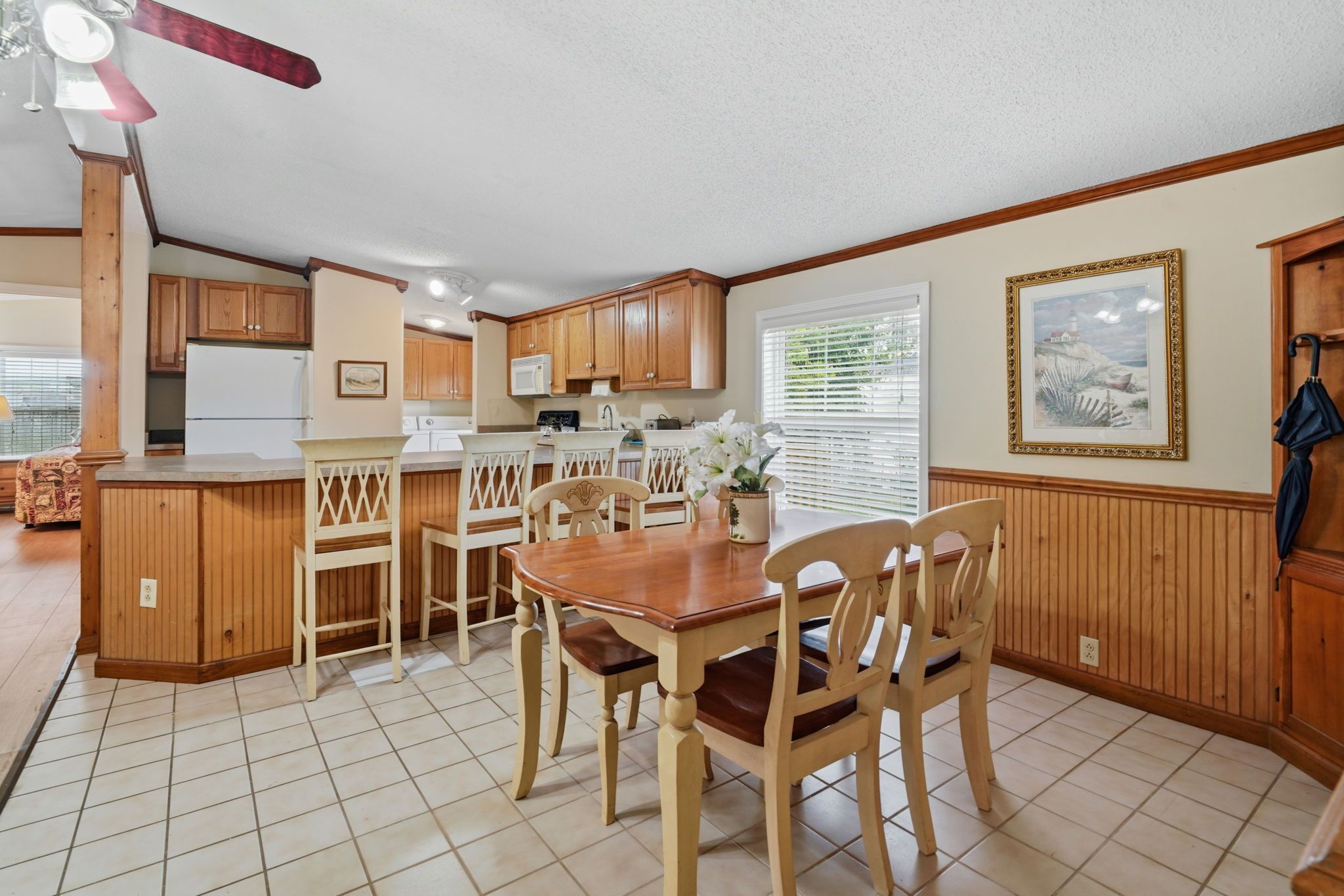 A kitchen with wooden cabinets, a dining table with chairs, and a ceiling fan.