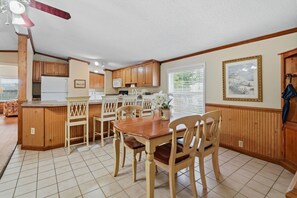 Una cocina con armarios de madera, una mesa de comedor con sillas y un ventilador de techo.