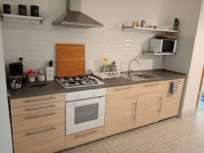Eine moderne Küche mit Gasherd, weißen Schränken, einer Mikrowelle und einem Edelstahl-Spülbecken.