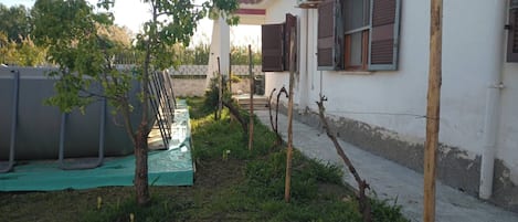 A residential building with a garden, a water tank, and a pergola structure.