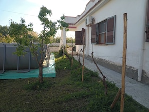 A residential building with a garden, a water tank, and a pergola structure.
