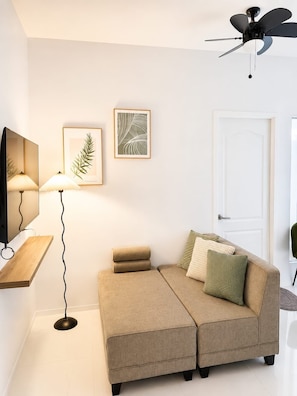 A modern living room with a sofa, a floor lamp, and framed artwork on the wall.