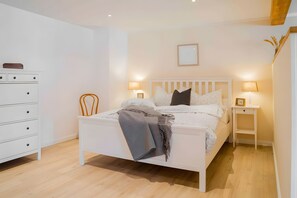 Ein Schlafzimmer mit einem Bett, Nachttischen, einer Kommode und einem gerahmten Bild an der Wand.