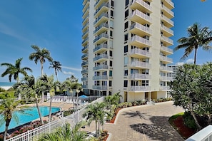 Ein mehrstöckiges Hotel mit Balkonen, einem Swimmingpool und Palmen.