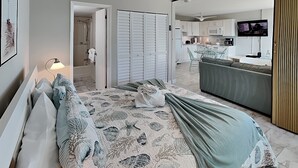 Un dormitorio con cama, mesita de noche, lámpara, baño con ducha y una zona de cocina con televisor.