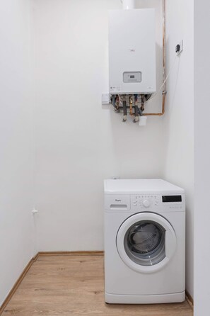 Ein Waschraum mit Waschmaschine und Warmwasserbereiter.