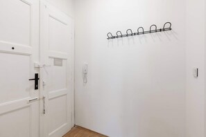 Eine weiße Tür mit schwarzem Griff, ein an der Wand befestigtes Telefon und ein Metallkleiderständer mit Haken.