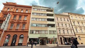 Ein mehrgeschossiges Gebäude mit einer Schaufensterfront, auf deren Erdgeschoss "EXAEIN" steht.