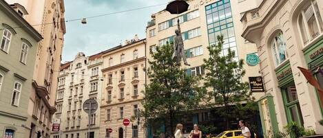 A street scene with outdoor seating, a statue, and buildings with signage.