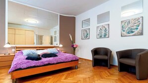 Ein modernes Schlafzimmer mit einem großen Bett, zwei Stühlen, einem Spiegel und Kunstwerken an den Wänden.