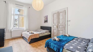 A bedroom with two beds, a radiator, a hanging light, and a door with a picture. - Old Town Suite Apartworld (Hlavní město Praha)