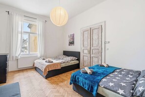 A bedroom with two beds, a radiator, a hanging light, and a door with a picture. - Old Town Suite Apartworld (Hlavní město Praha)