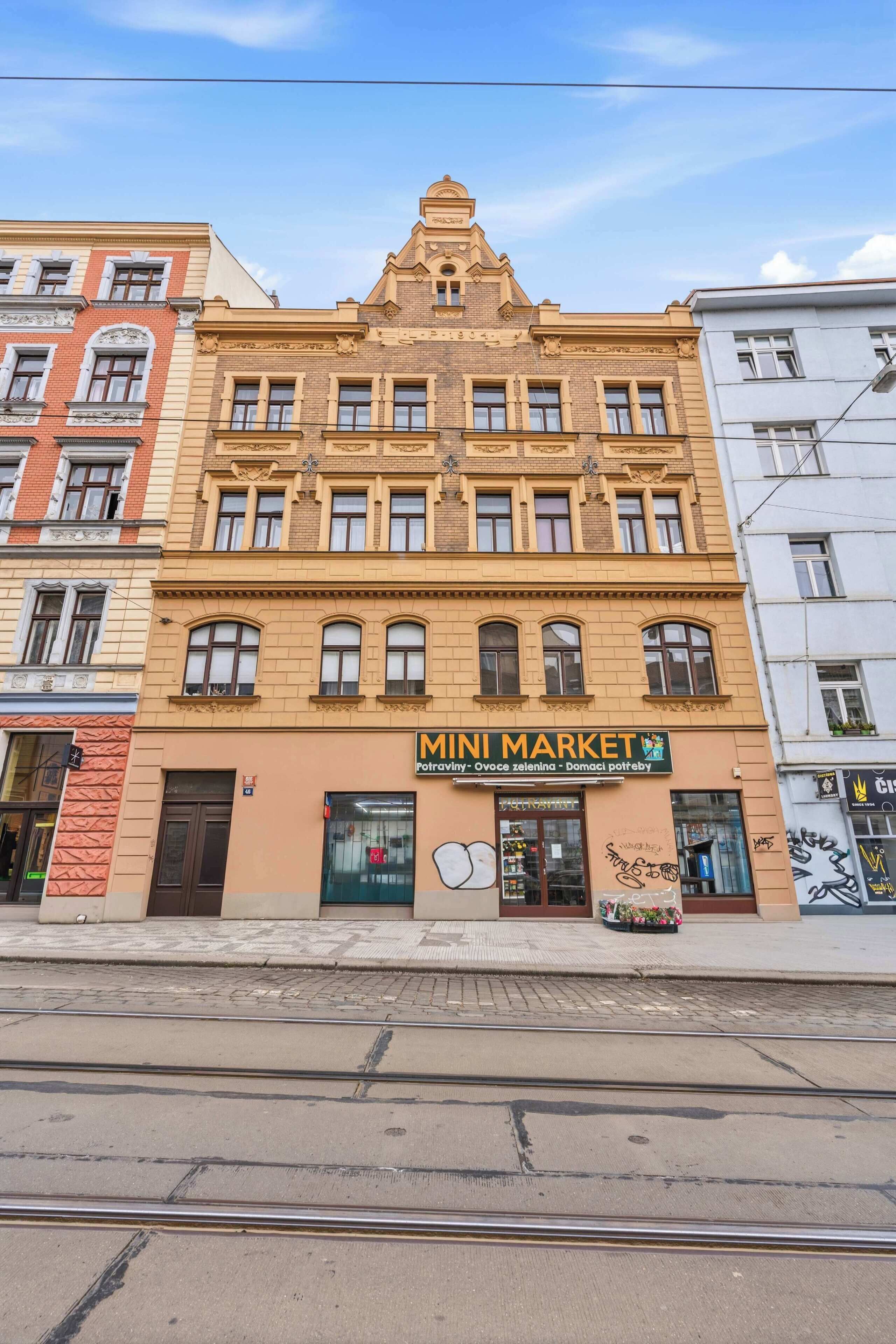 A building with a storefront labeled 'MINI MARKET' featuring a traditional architectural style with multiple windows and a central entrance.