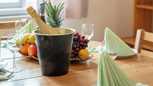 A dining table with a bottle of champagne, a pineapple, and a basket of fruits. - Old Town Suite Apartworld (Hlavní město Praha)