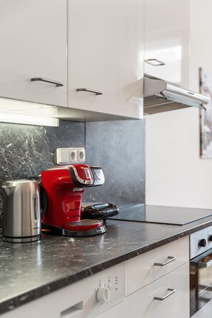 A kitchen with a red coffee maker, a kettle, and a stove. - Old Town Suite Apartworld (Hlavní město Praha)