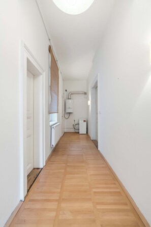 A narrow hallway with wooden flooring, white walls, and a radiator. - Old Town Suite Apartworld (Hlavní město Praha)