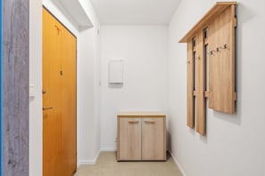 A hallway with a wooden door, a small cabinet, and a wall-mounted wooden unit with hooks. - Secret Courtyard Residence Apartworld (Praha)