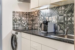 A kitchen with a washing machine, a coffee maker, and a sink. - Secret Courtyard Residence Apartworld (Praha)