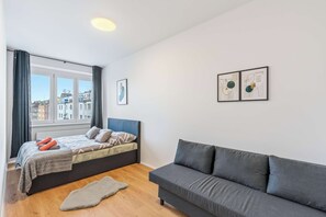 A modern bedroom with a bed, grey sofa, and artwork on the wall.
